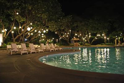 Concrete pool deck with cute lounge chairs over looking pool at night