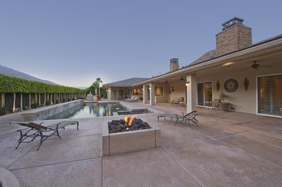 Decorative concrete pool deck and patio with lounge chairs and modern built in fire pit
